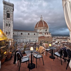 Una terraza con asientos al aire libre y vistas a un edificio histórico con una torre de campanas y una cúpula.