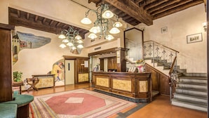 Un vestíbulo con mostrador de recepción de madera, una escalera y una alfombra grande con diseño.