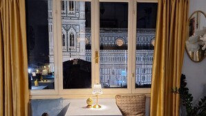 A dining area with a table set for two, a view of a historic building, and a potted plant. - Hotel De Lanzi (Florence)