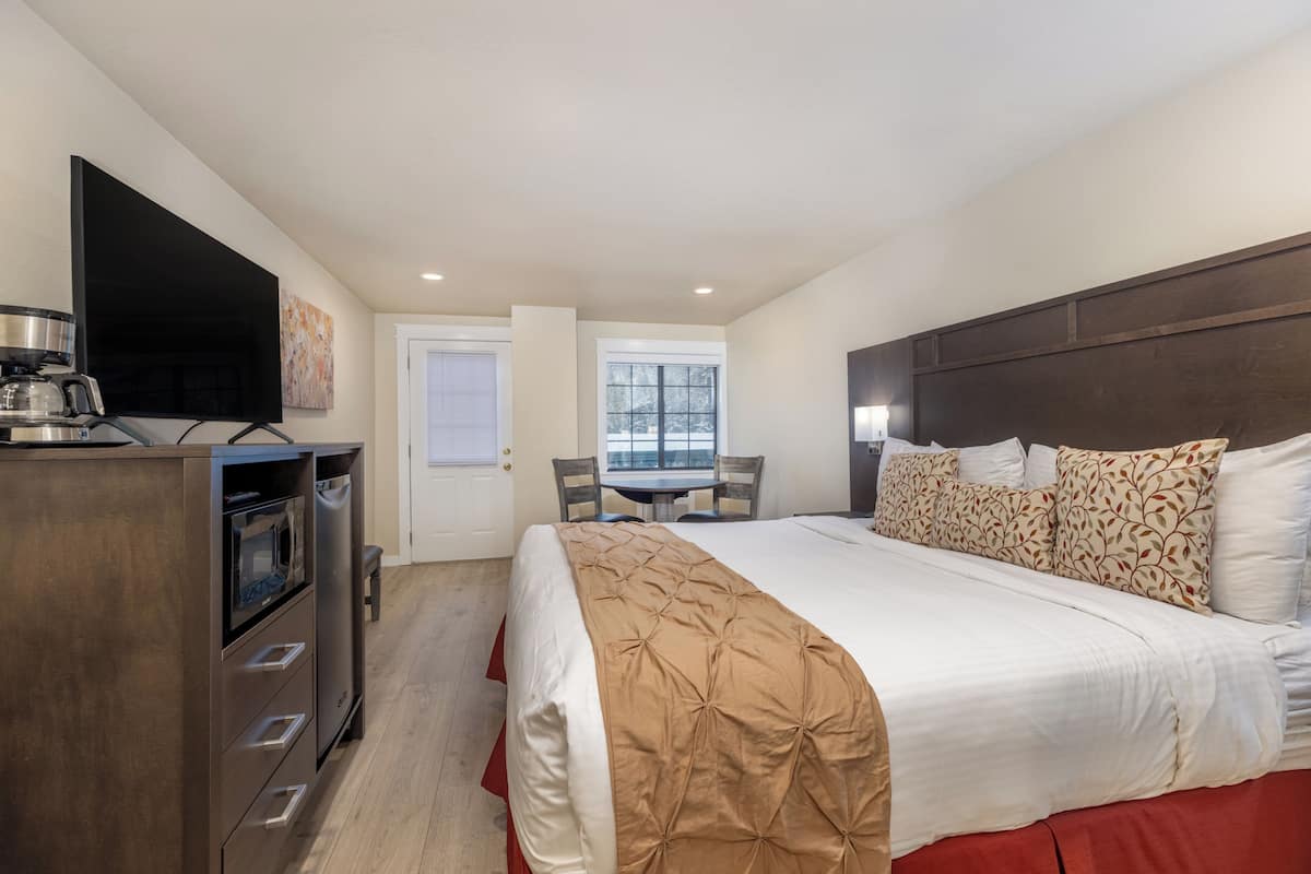 A hotel room with a bed, a desk, a coffee maker, and a TV.