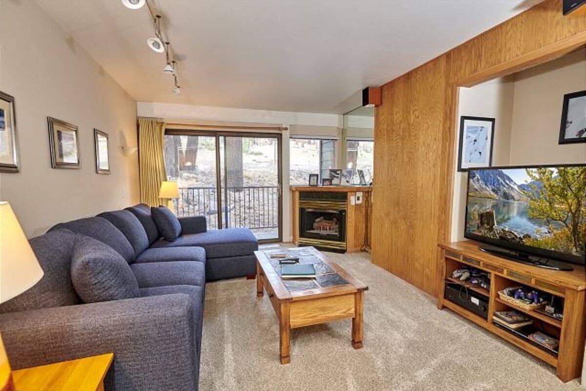 A living room with a sofa, coffee table, TV stand, and fireplace.