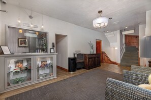 A reception area with a counter, framed pictures, a trash bin, and a staircase.