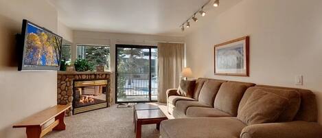 A living room with a fireplace, a sofa, a coffee table, and a TV.