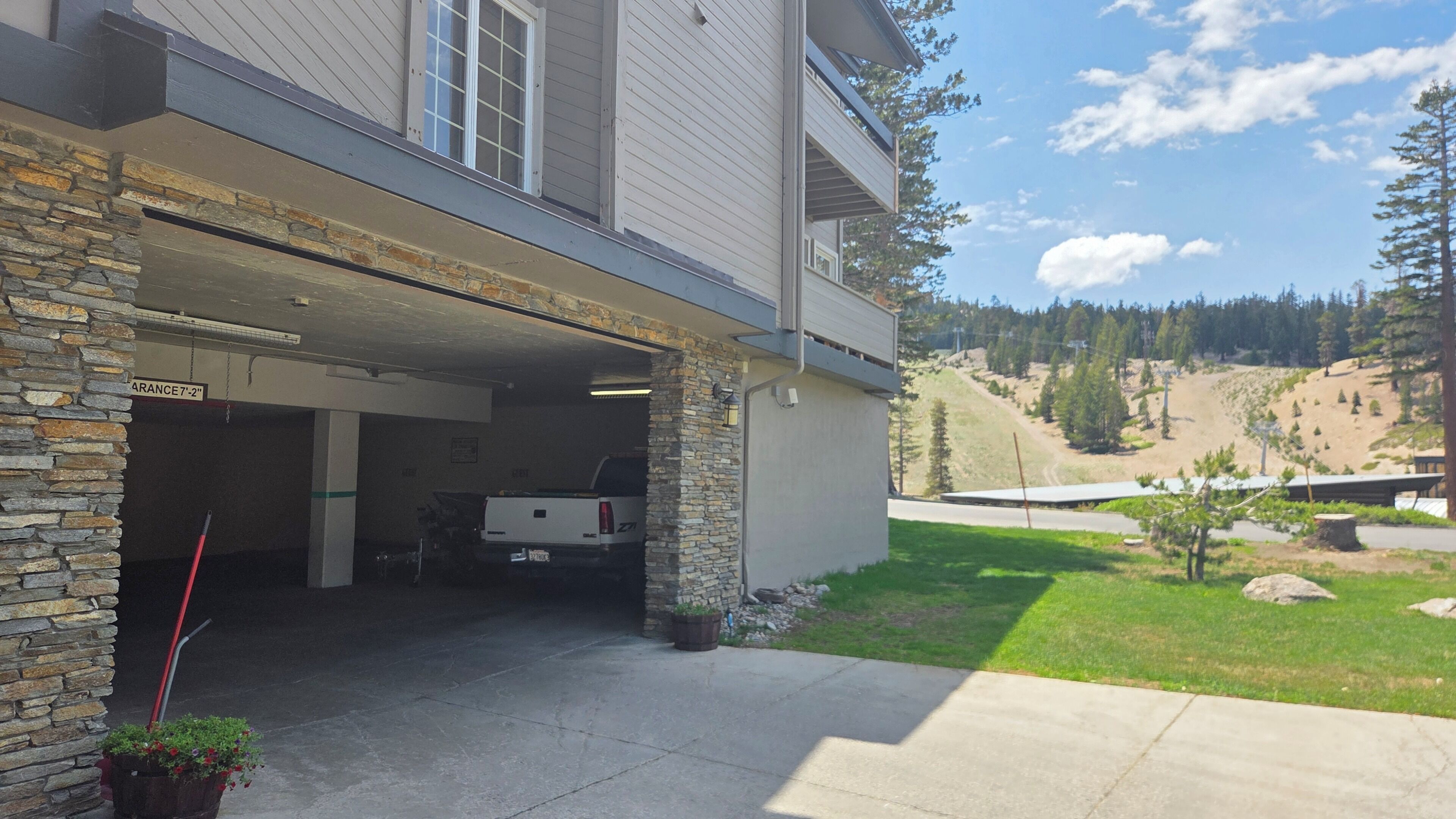 A two-story building with a garage entrance, stone pillars, and a vehicle parked inside.