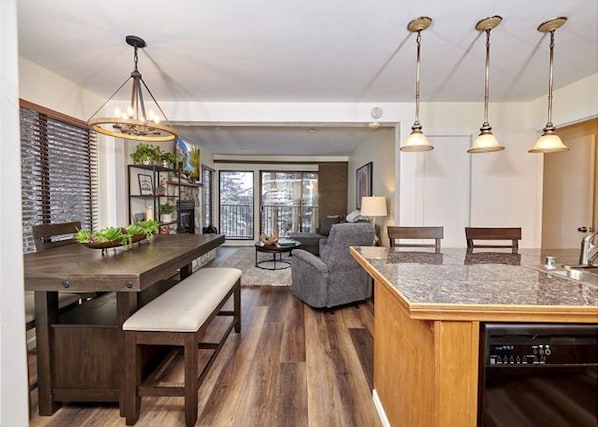 A modern kitchen with a dining area, wooden flooring, and a built-in dishwasher. - Austria Hof Lodge (Mammoth Lakes)