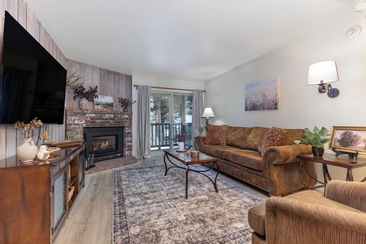 A living room with a fireplace, sofa, coffee table, and a flat-screen TV.