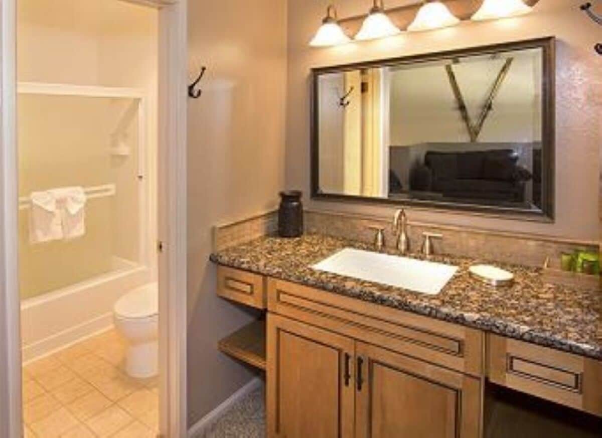 A bathroom with a sink, mirror, and a toilet.