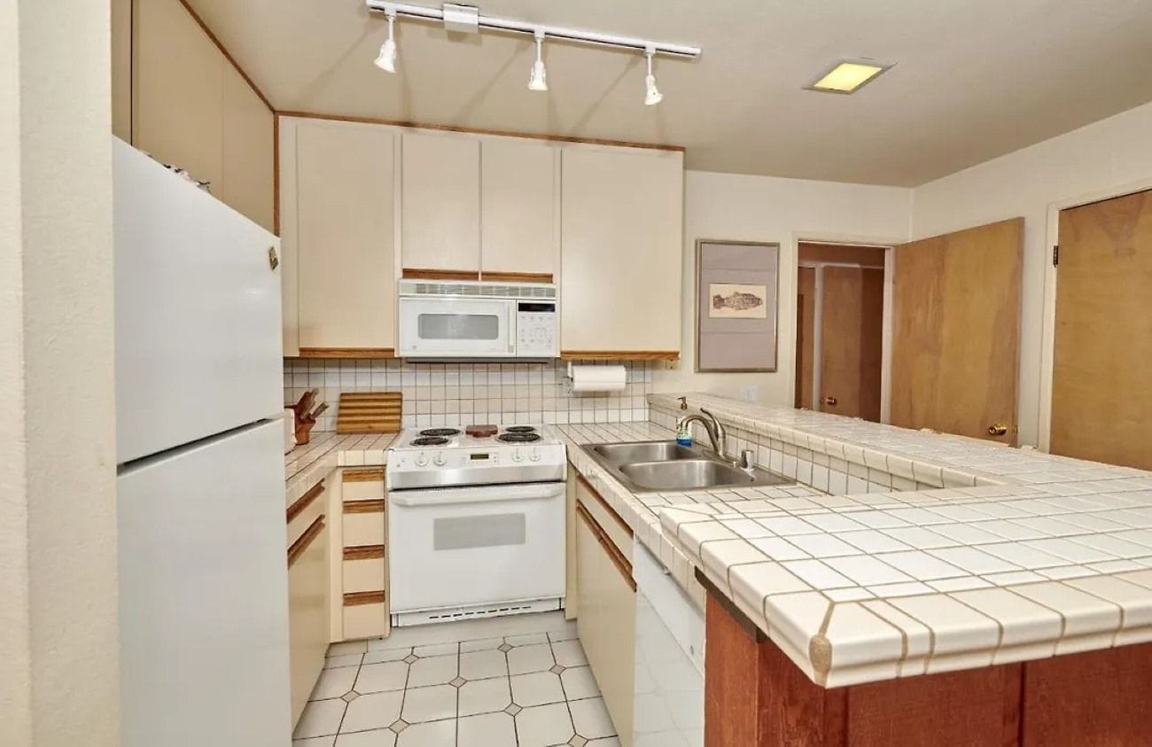 A compact kitchen with a refrigerator, stove, microwave, and sink.
