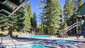 Ein Poolbereich mit zwei Whirlpools, umgeben von Bäumen und einem Gebäude mit einer überdachten Terrasse.