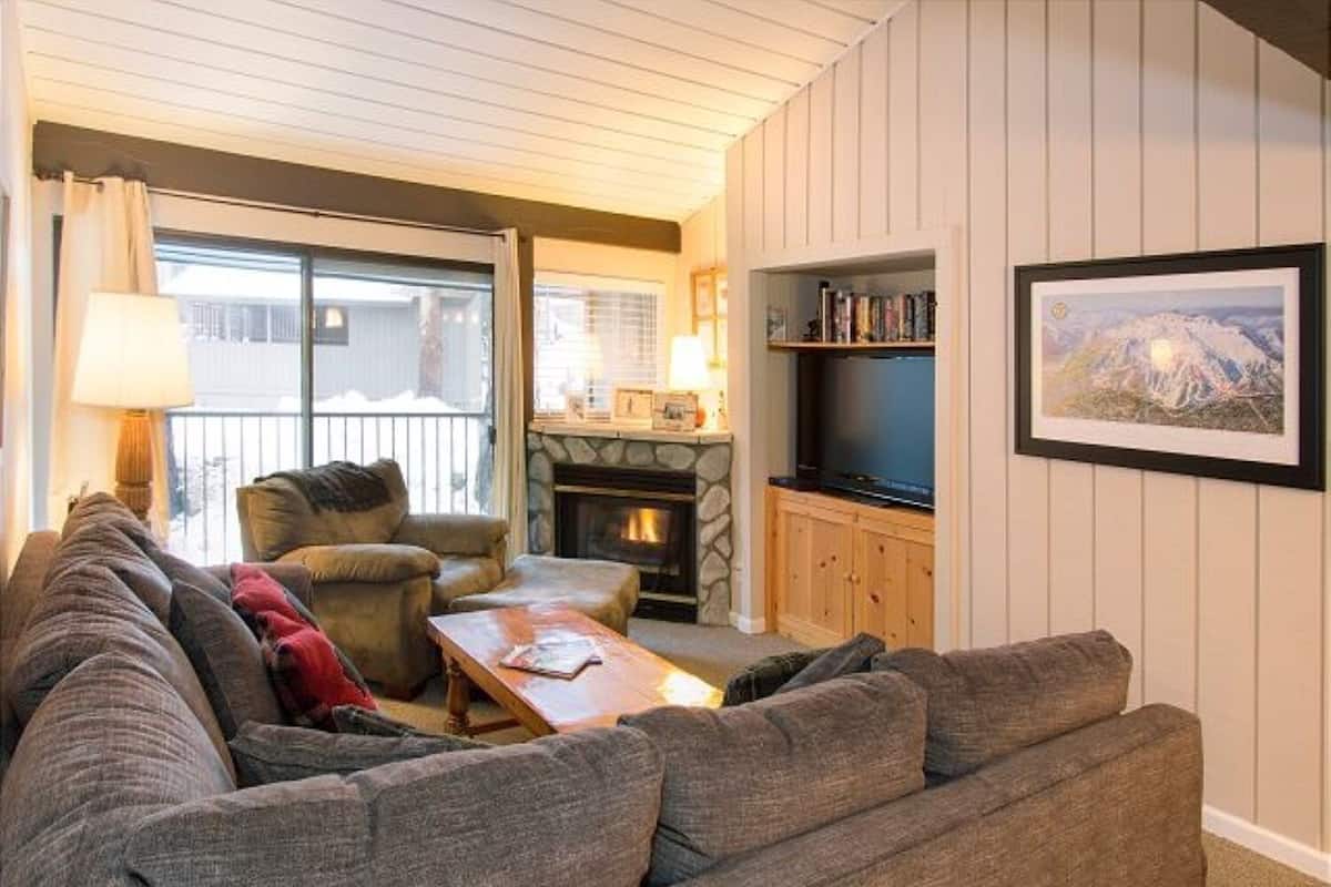 A cozy living room with a fireplace, a television, and a bookshelf.