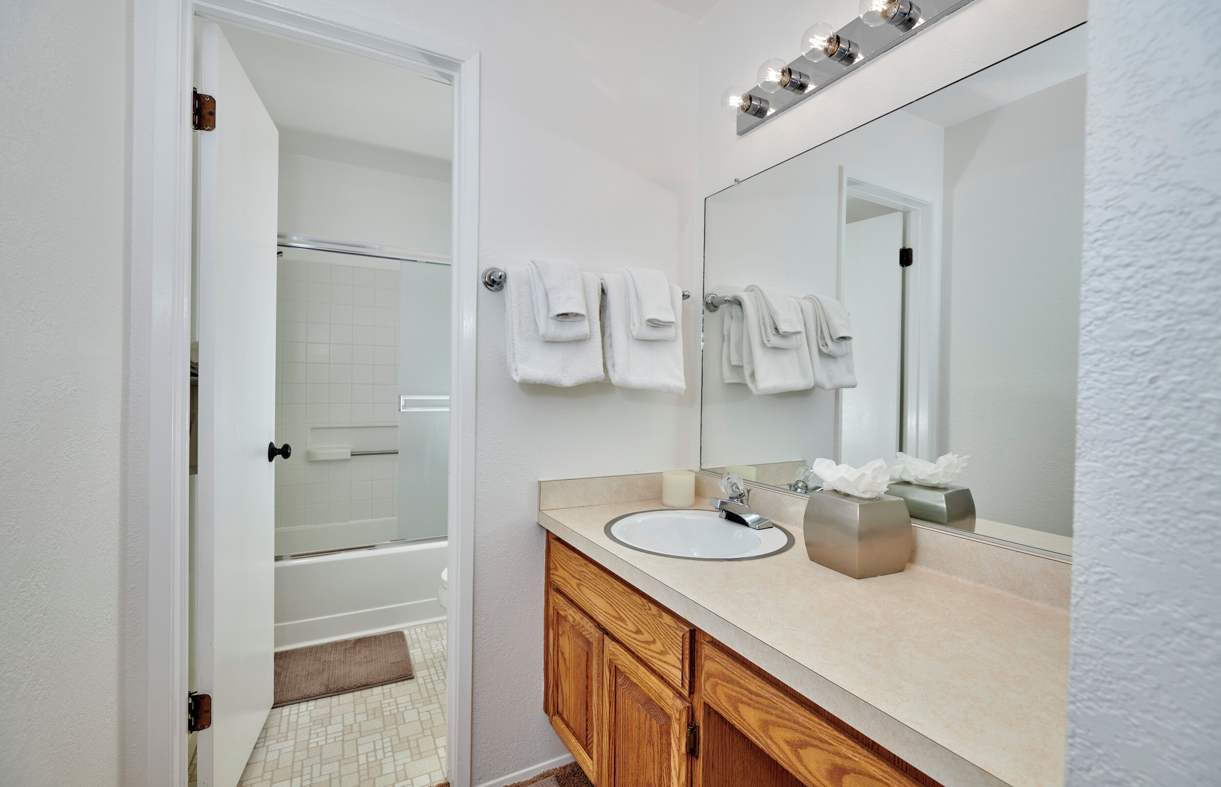 Une salle de bain avec un lavabo blanc, un meuble-lavabo en bois et un grand miroir.