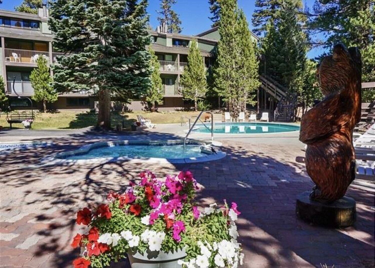 A pool area with a fountain, surrounded by potted flowers and a sculpture.