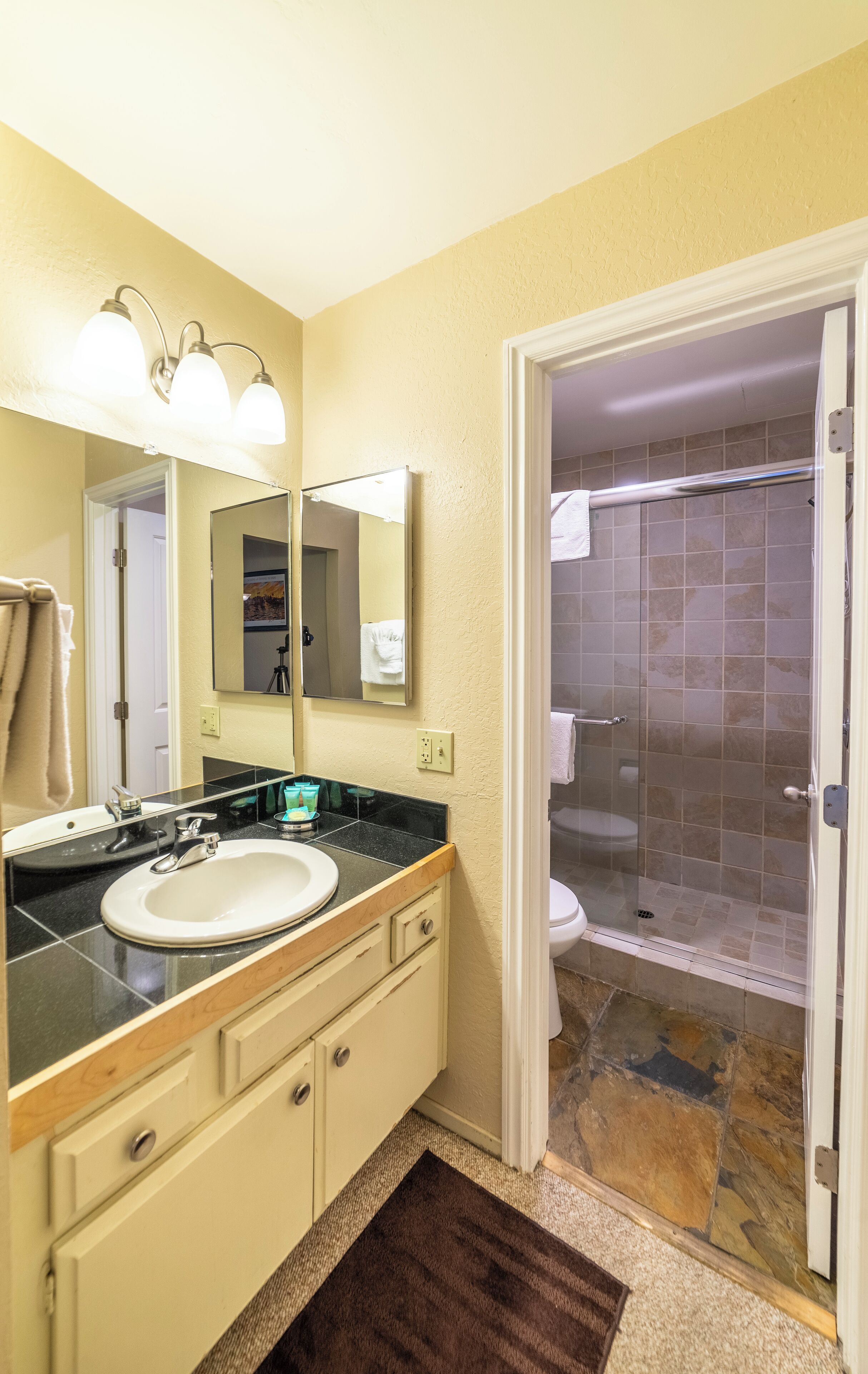 Een badkamer met een wastafel, spiegel en douche.