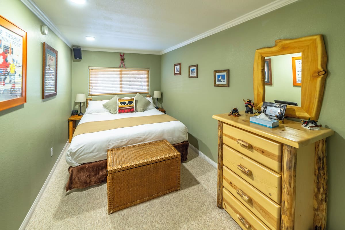 A bedroom with a bed, dresser, and a mirror.