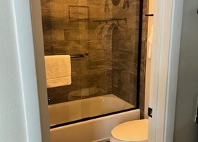 Un bagno con doccia vetrata, vasca da bagno bianca e water.