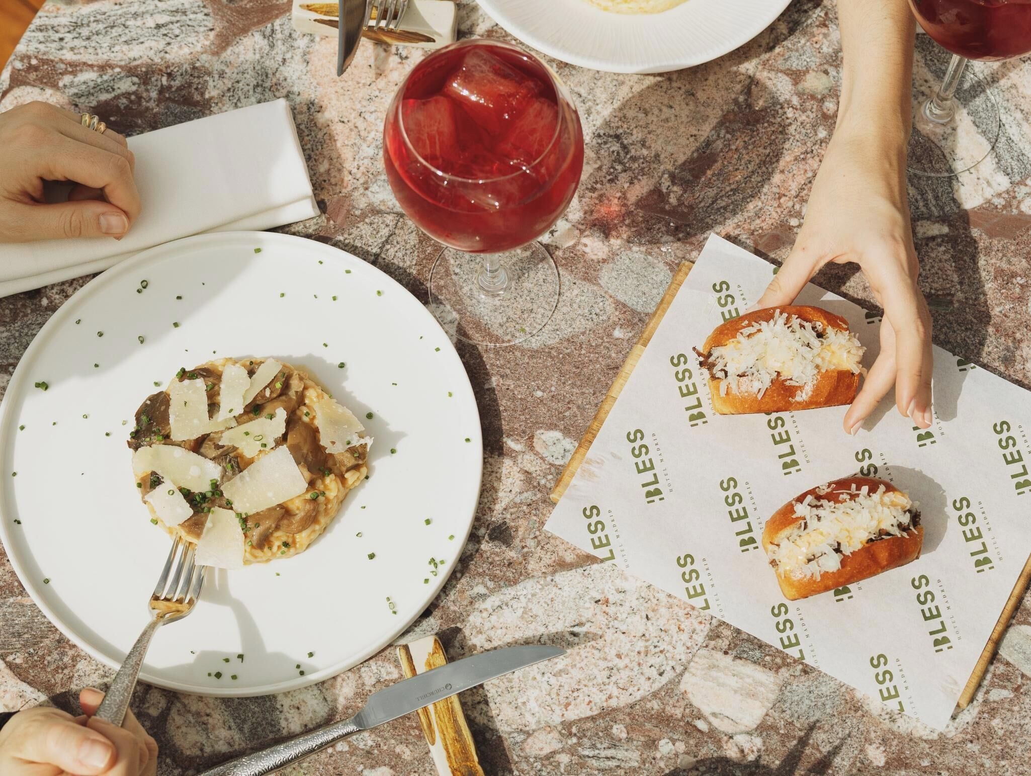 A dining table with a plate of food, a glass of red drink, and a menu.