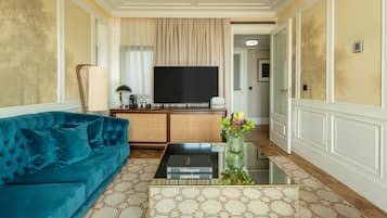 A living room with a blue sofa, a coffee table with books, a TV, and a decorative vase.