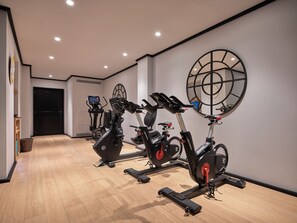 A gym with multiple stationary bikes and treadmills, wooden flooring, and a large wall clock. - BLESS Madrid - The Leading Hotels of the World (Madrid)