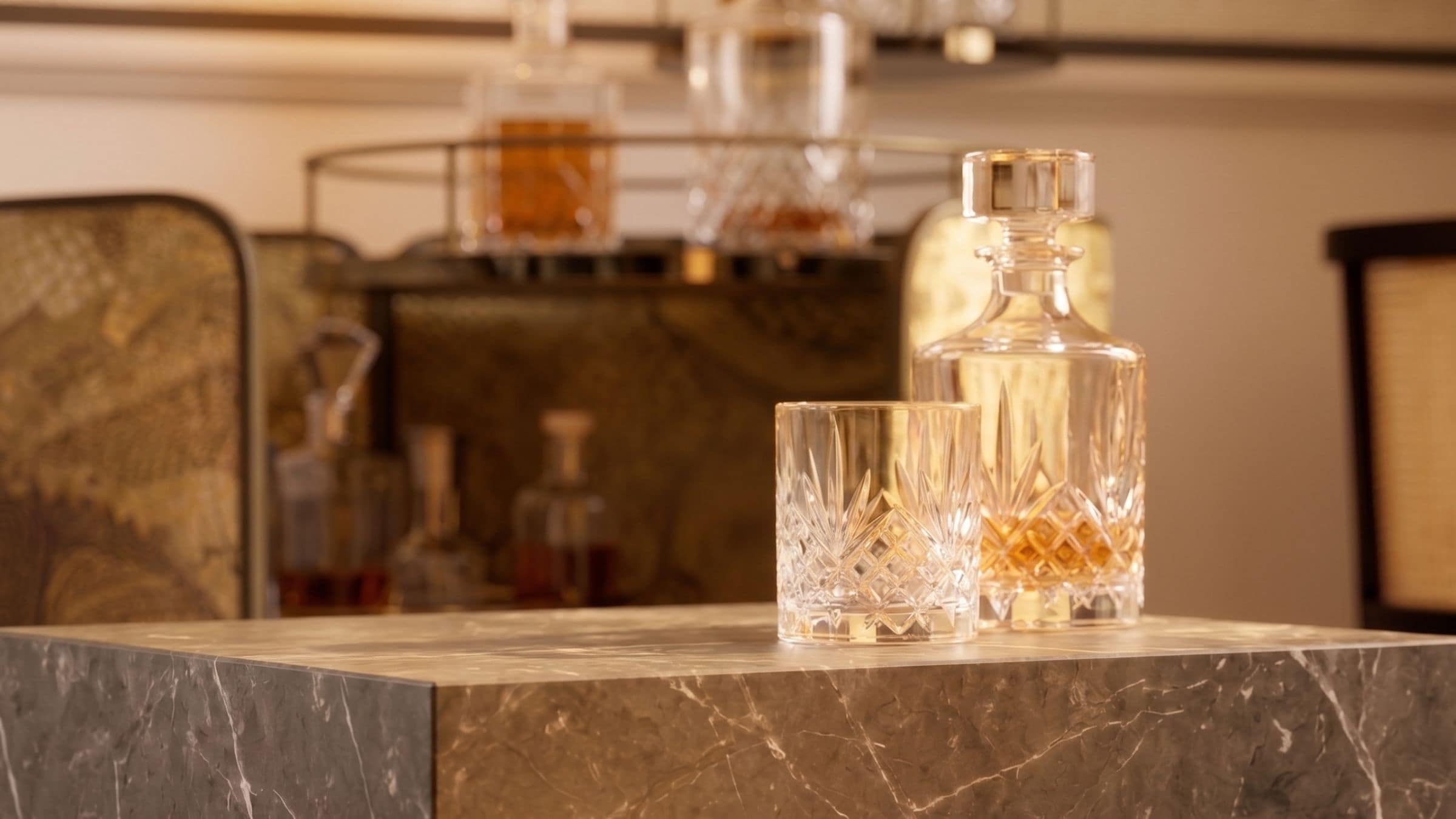 A marble countertop with a crystal decanter and a glass.