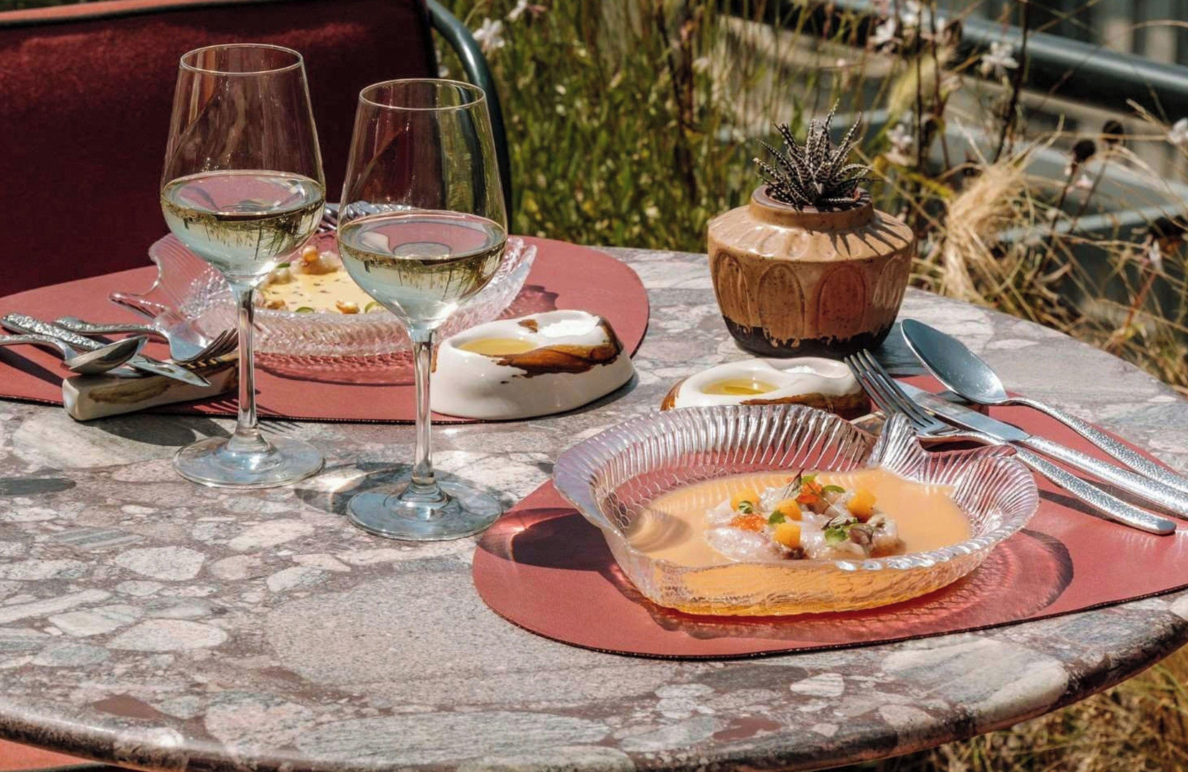Een gedekte tafel met wijnglazen, een soepkom en een decoratieve pot.