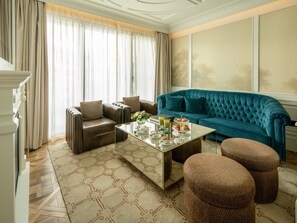 A living room with a brown leather sofa, a teal sofa, and a glass coffee table with a floral centerpiece.