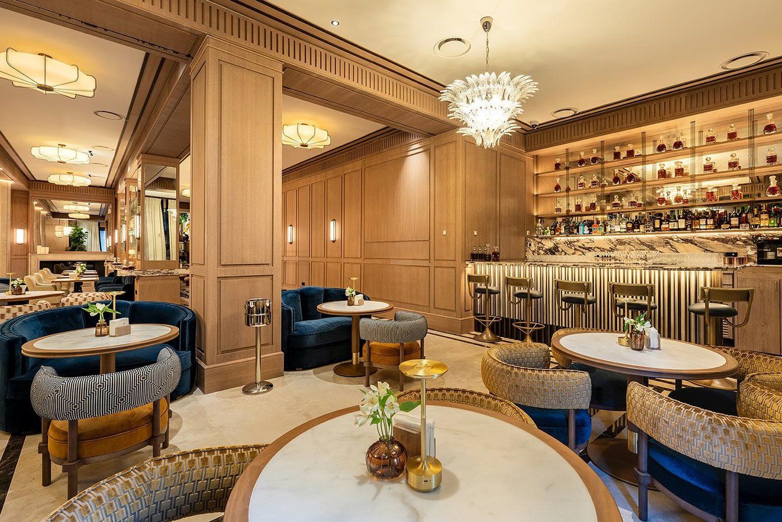 A luxurious bar area with multiple seating options, including round tables and bar stools.