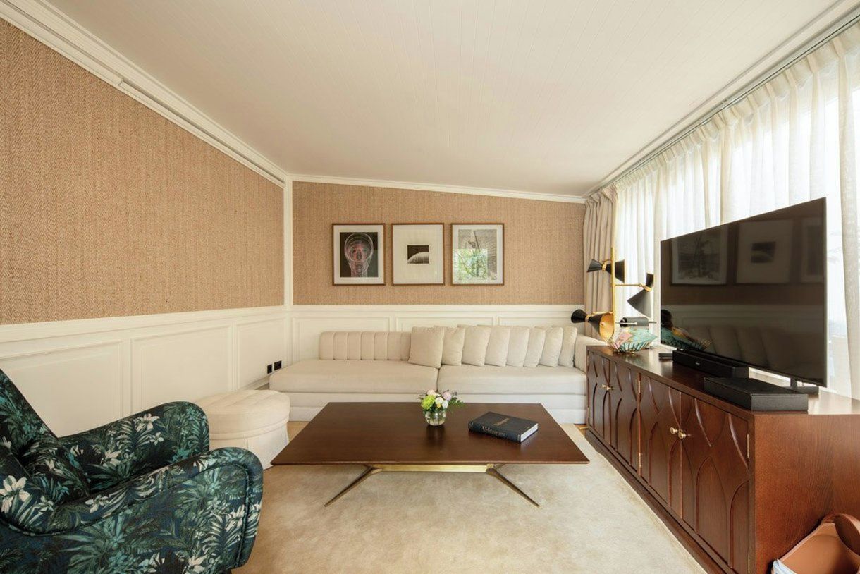 A living room with a sofa, a coffee table, a television, and framed pictures on the wall.