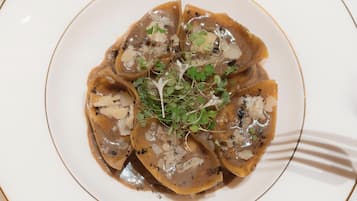 A plate of ravioli with a creamy sauce and garnished with herbs.