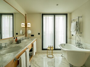 A modern bathroom with a marble sink, a freestanding bathtub, and a large mirror with lights. - BLESS Madrid - The Leading Hotels of the World (Madrid)