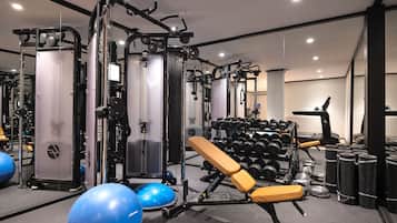 Un gimnasio con equipo de ejercicio, bancos de halterofilia y pelotas de entrenamiento.