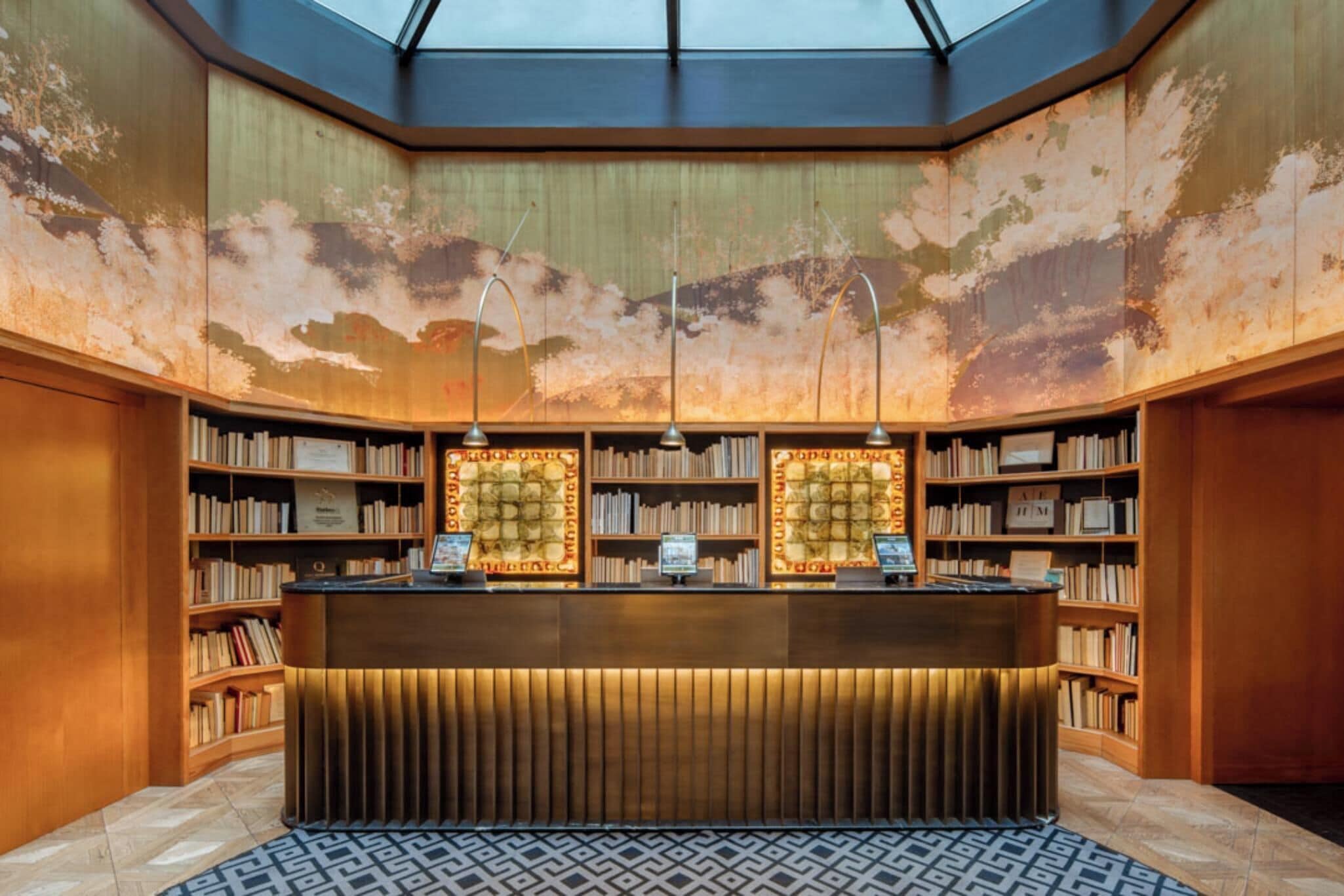 Una biblioteca con tragaluces, estanterías y un mostrador de recepción.