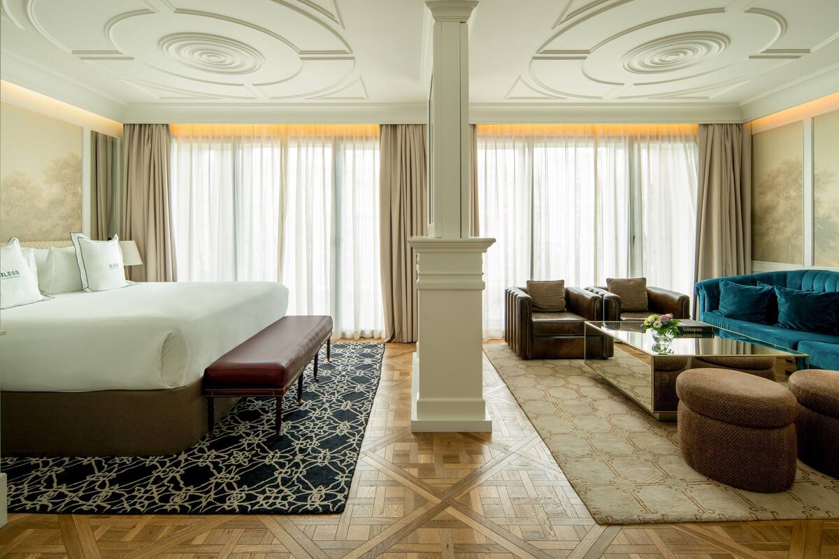 A hotel room with a large bed, a sofa, a coffee table, and a decorative pillar.