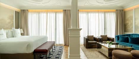 A hotel room with a large bed, a sofa, a coffee table, and a decorative pillar.