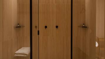 A modern bathroom with a glass partition, wooden paneling, and a towel rack.