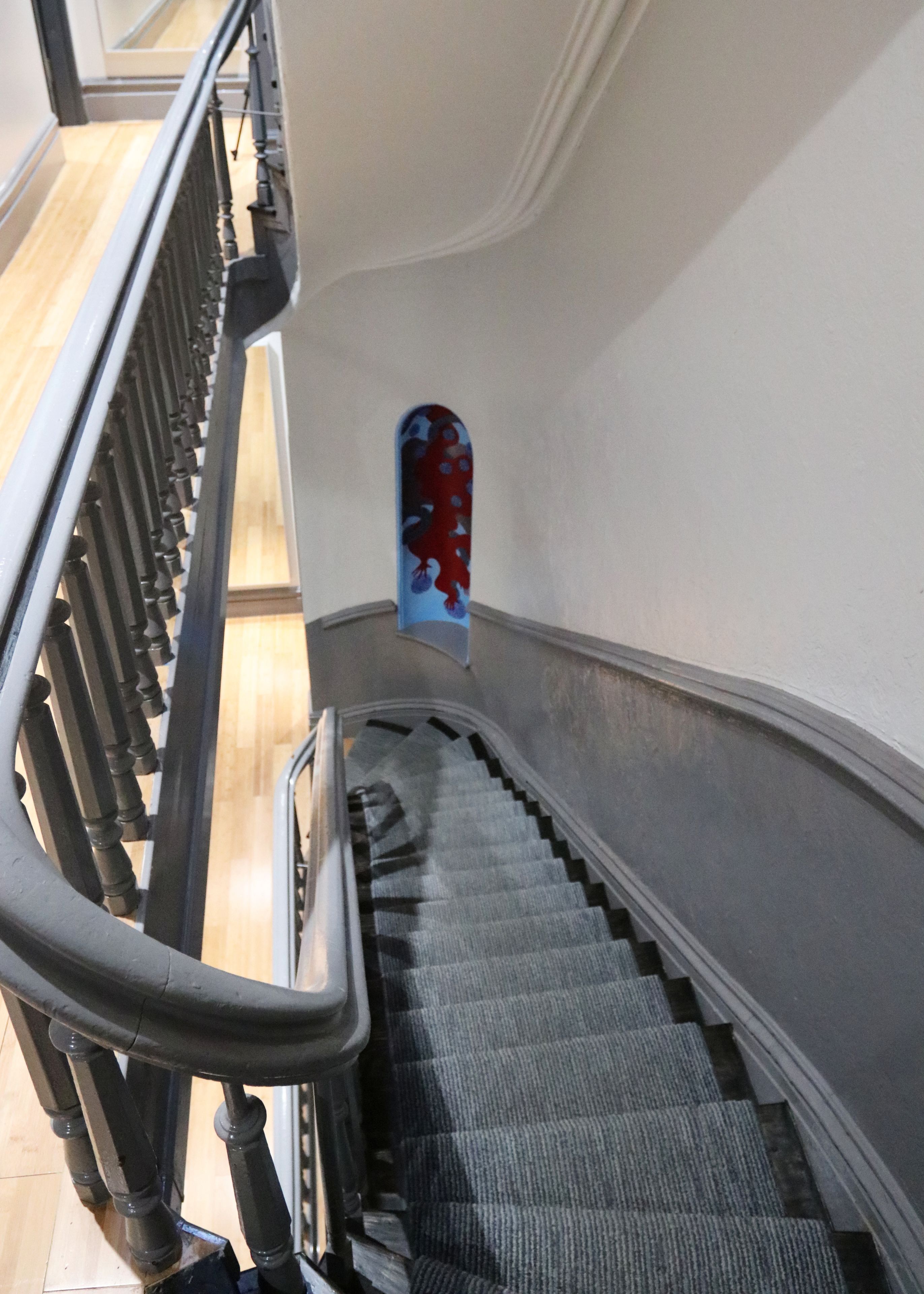 A staircase with a handrail, carpeted steps, and a wall with a decorative panel.