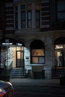 A Chelsea Inn hotel entrance with a black awning, steps leading up to the door, and a brick facade.