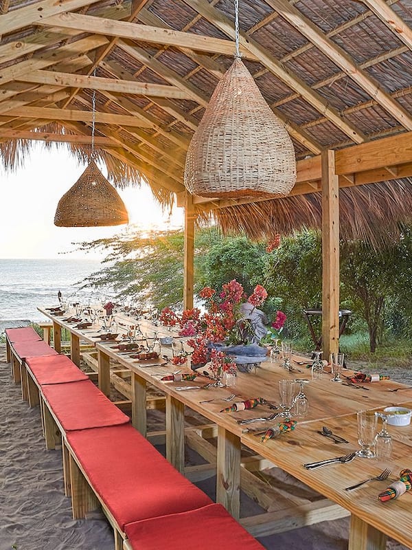 Enjoy a meal under the shade of a rustic structure on the beach.