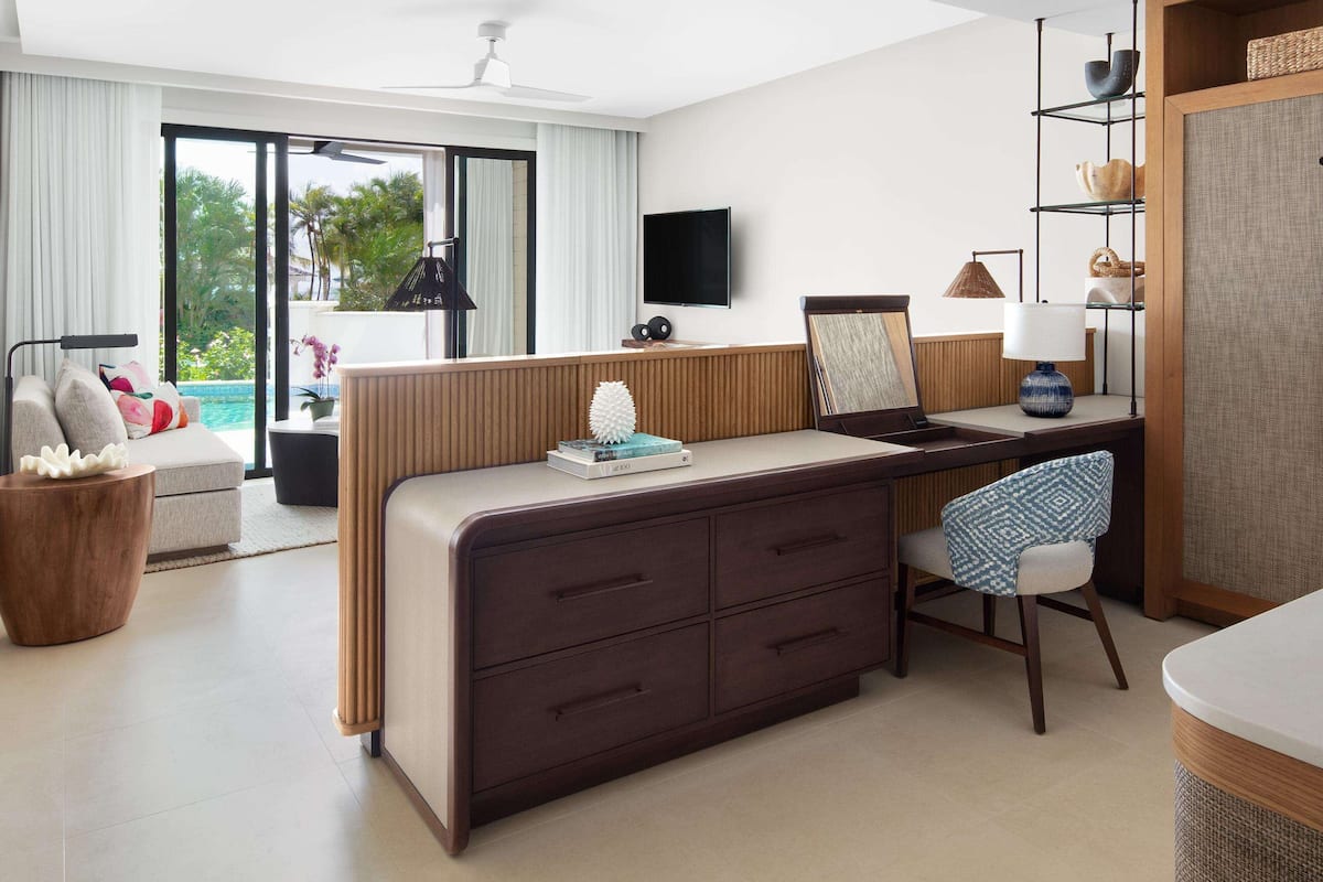 Habitación de hotel moderna con escritorio, silla y vista a una piscina.