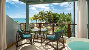 A balcony with wicker chairs and a glass table, overlooking a beach with palm trees and a view of the ocean. - Sandals Negril - ALL INCLUSIVE Adults Only (Negril)