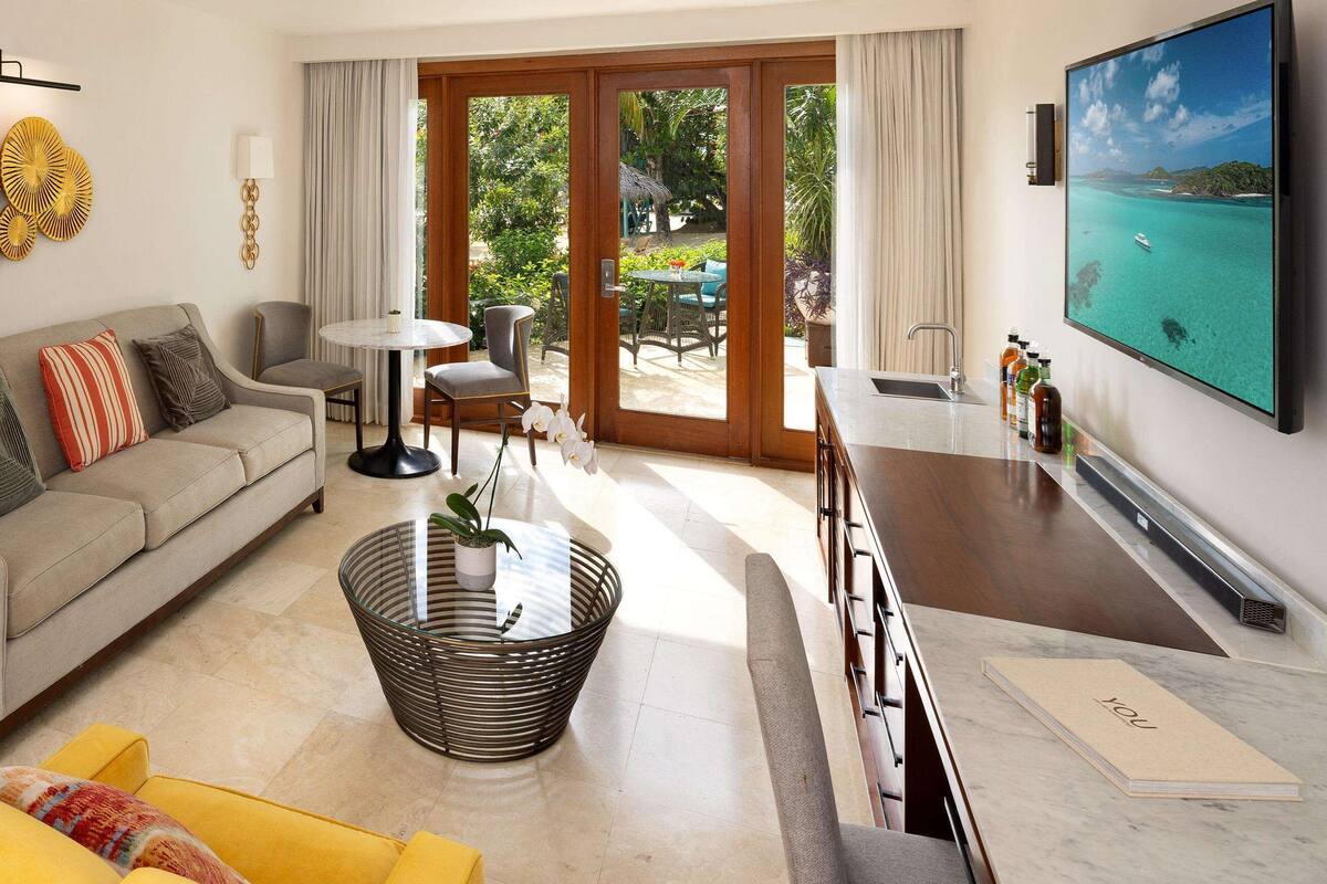 Una sala de estar moderna con sofá, sillones, una mesita de centro y televisor.