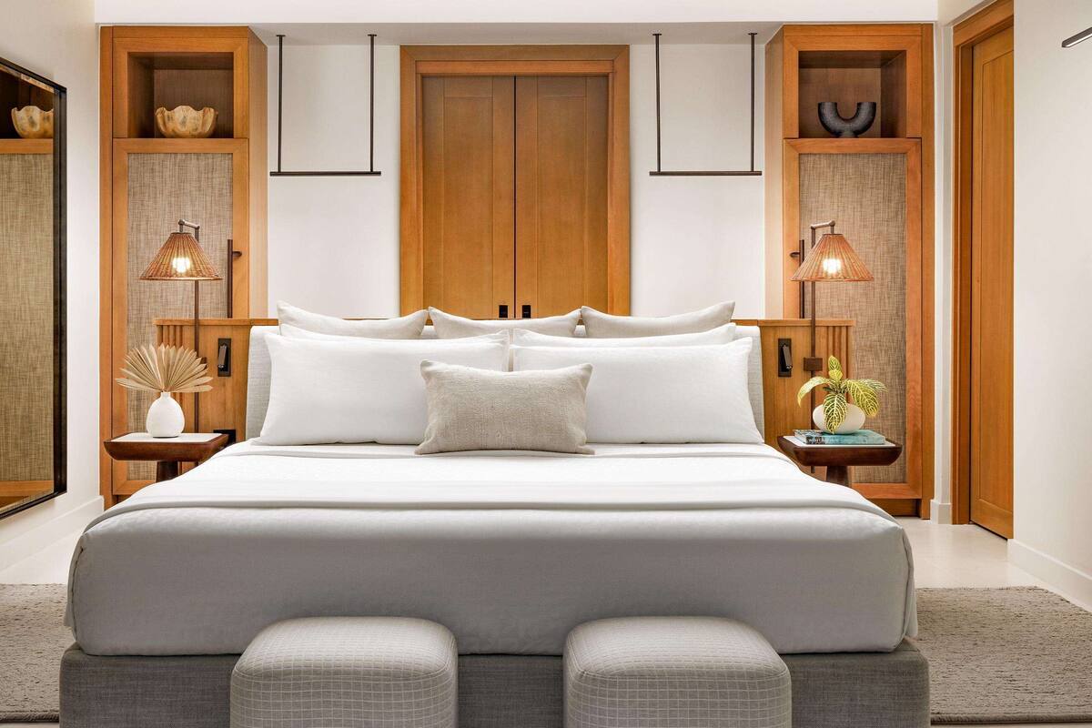 Un dormitorio moderno con una cama grande, un armario de madera y lámparas de noche.