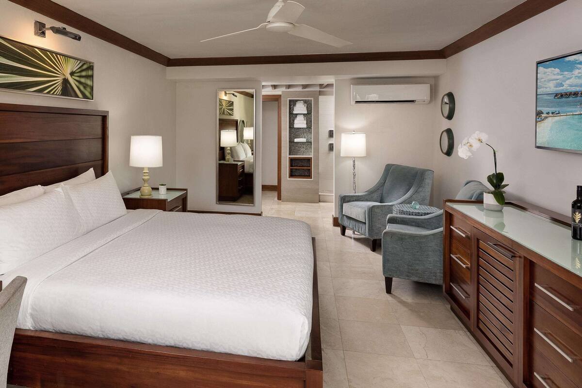 Una habitación de hotel con una cama grande, un escritorio, una silla, un televisor y un minibar.
