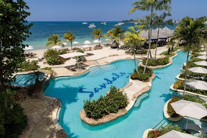 A resort pool with 'Sandals' written in the water, surrounded by palm trees, beach chairs, and umbrellas. - Sandals Negril - ALL INCLUSIVE Adults Only (Negril)