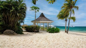 A beach with a gazebo, palm trees, and a boat in the water. - Sandals Negril - ALL INCLUSIVE Adults Only (Negril)