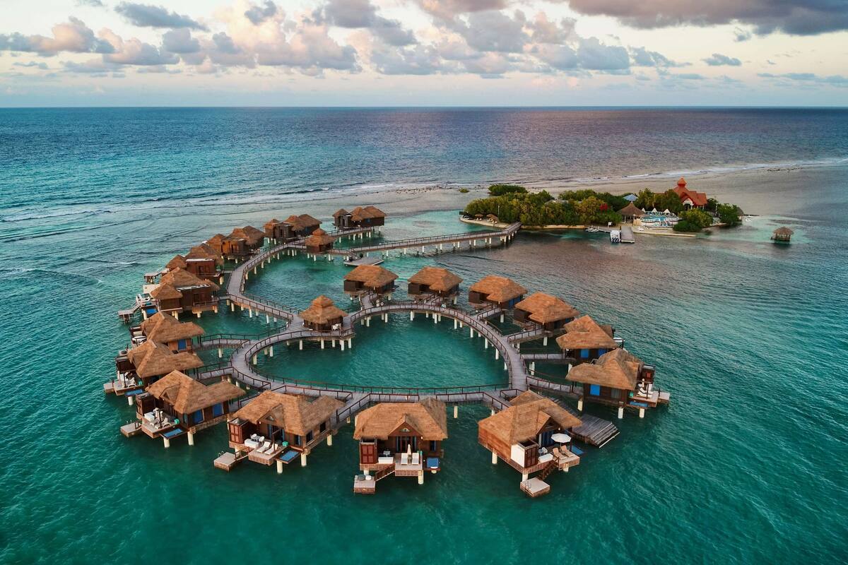 Des bungalows sur pilotis dotés de toits de chaume et reliés par des passerelles en bois, le tout entouré d’eaux turquoise.
