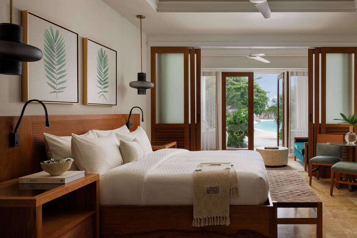 Une chambre d’hôtel moderne avec un grand lit, une tête de lit en bois, une télévision et une vue sur la plage.