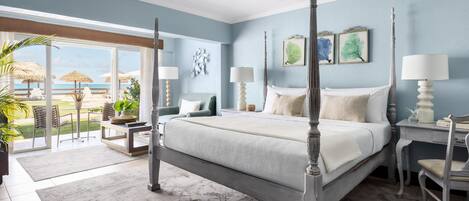A bedroom with a four-poster bed, a balcony with a view of the beach, and a dining area with a table and chairs.