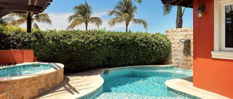 A swimming pool with a tiled edge, surrounded by lush greenery and palm trees.