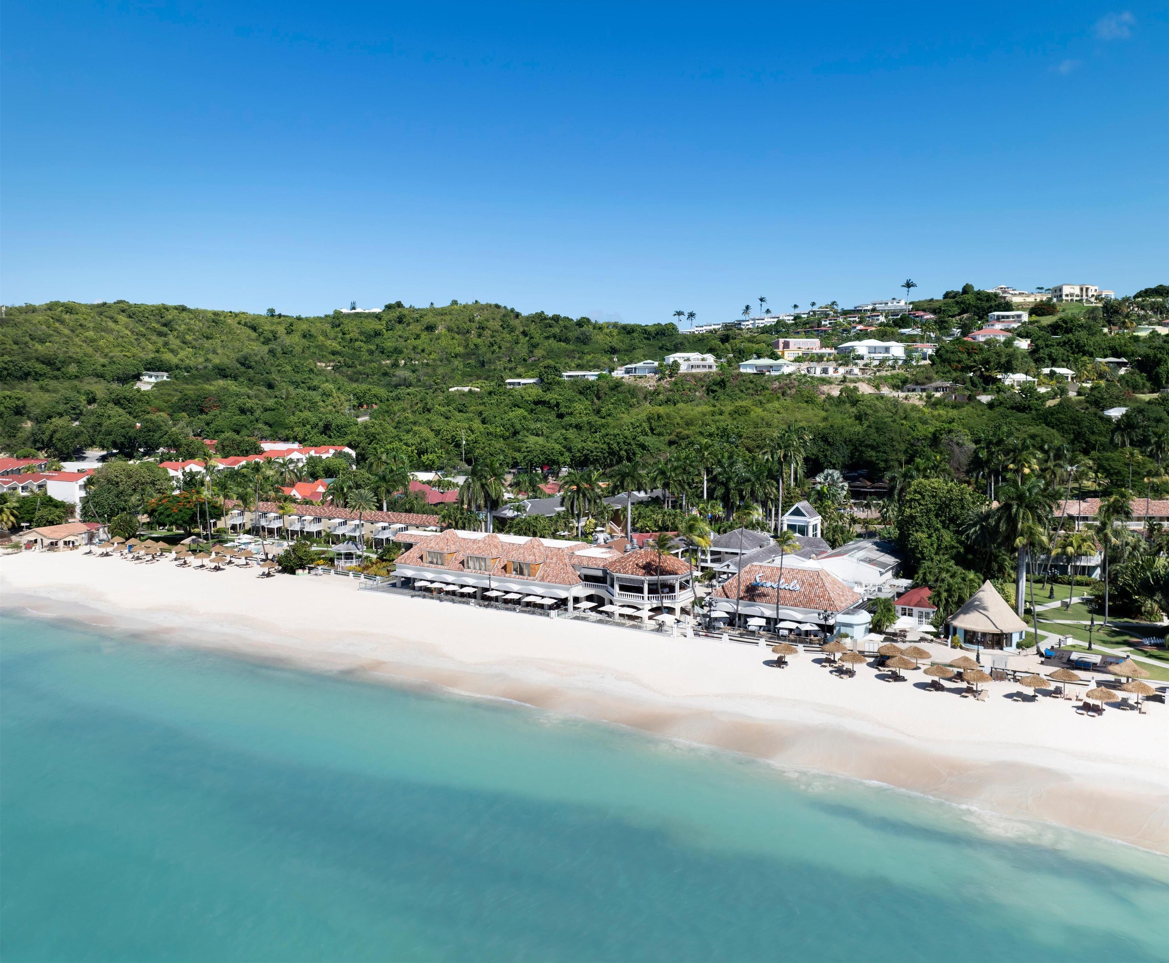 Une station balnéaire dotée de villas en bord de mer, d’une piscine et d’un restaurant au toit de chaume.