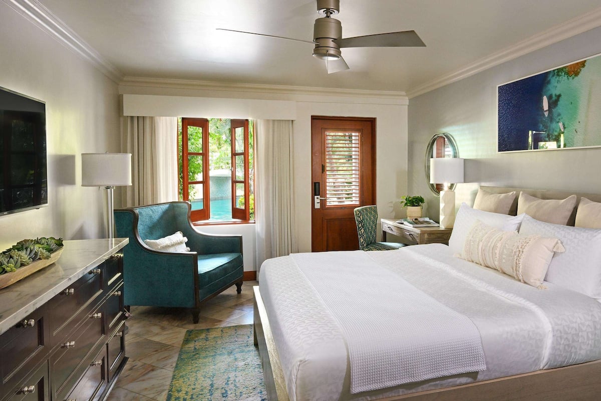 A hotel room with a large bed, a desk, a chair, and a TV.